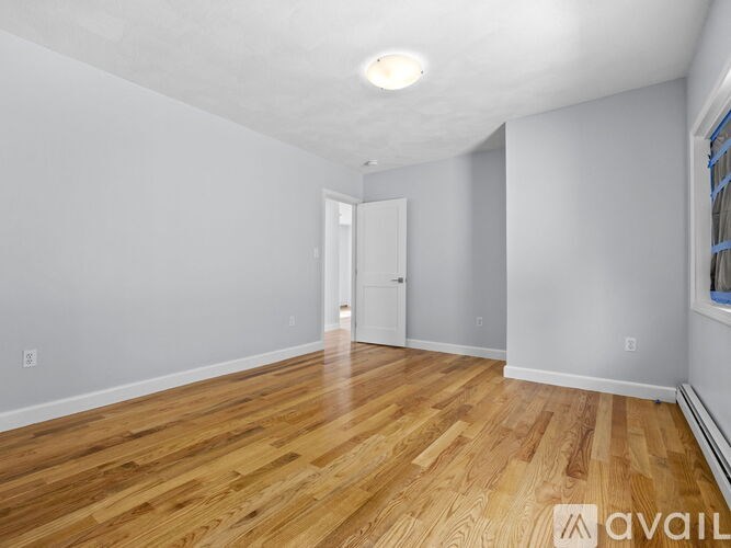 A room with wooden flooring and white walls is available for rent.