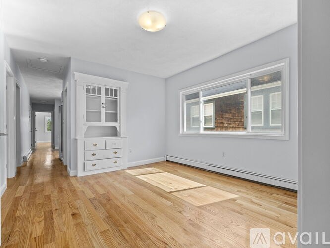 A spacious room with wooden flooring and a large window.