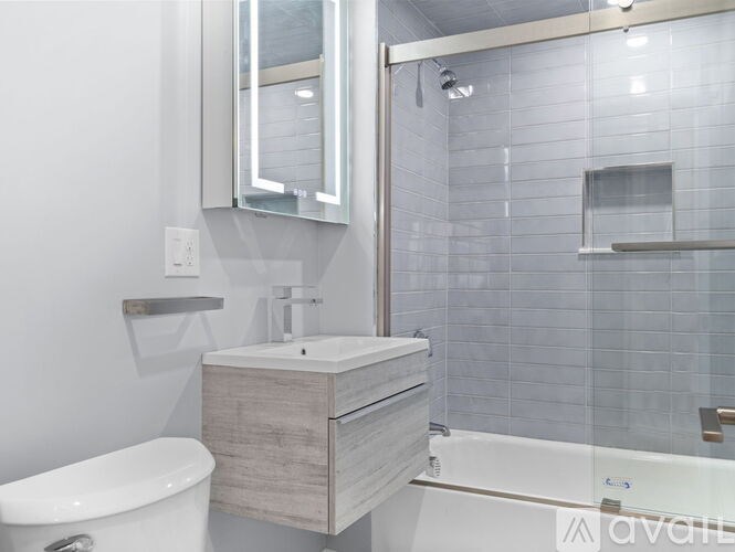 A modern bathroom with a white toilet, a wooden cabinet, and a glass shower area.