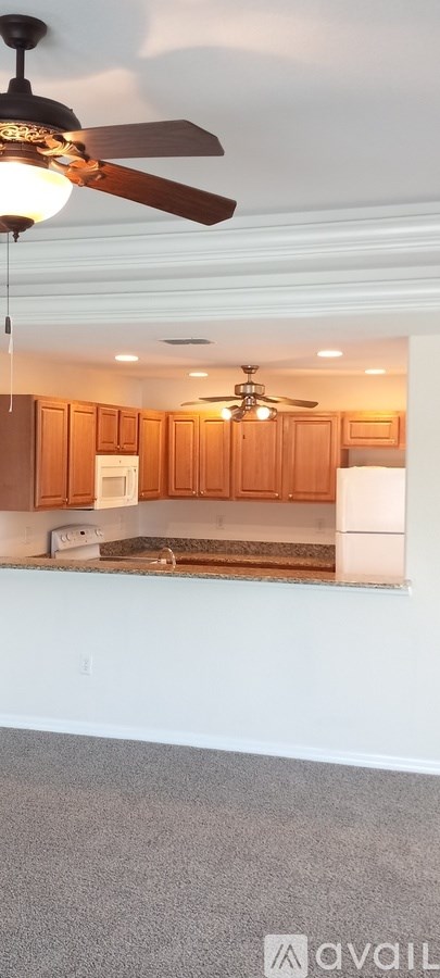 A kitchen with wooden cabinets and a ceiling fan.
