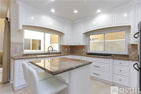 A kitchen with white cabinets and a marble countertop.