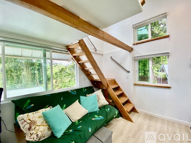A living room with a green couch and a wooden staircase.