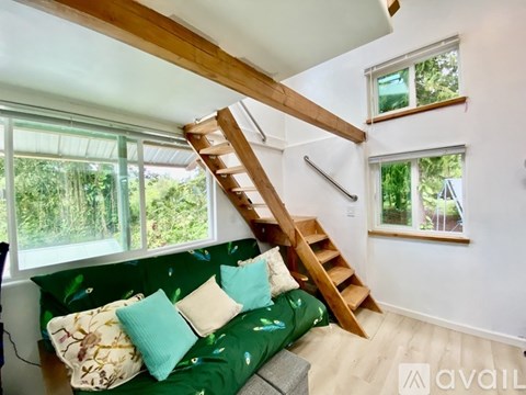 A living room with a green couch and a wooden staircase.
