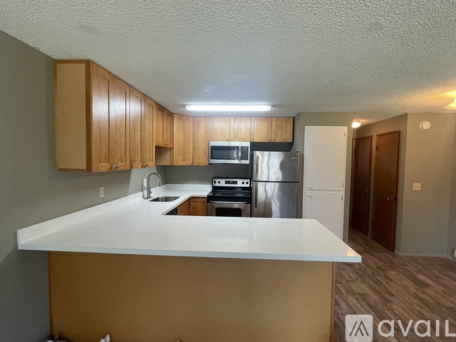 A kitchen with a white countertop and wooden cabinets.