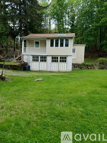A house with a white garage door is surrounded by a green lawn.