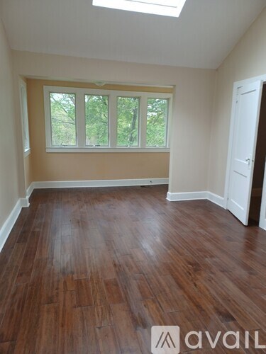 A room with wooden flooring and a window with white blinds.