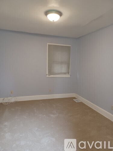 A room with a window and a white baseboard heater.