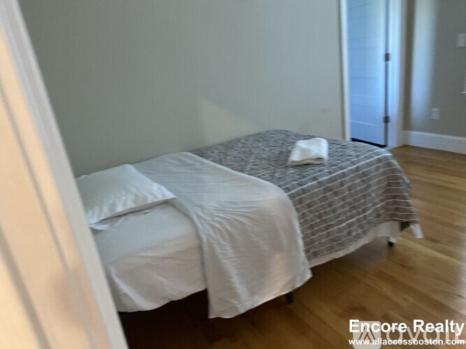 A bed with a white pillow and a white blanket is in the image.