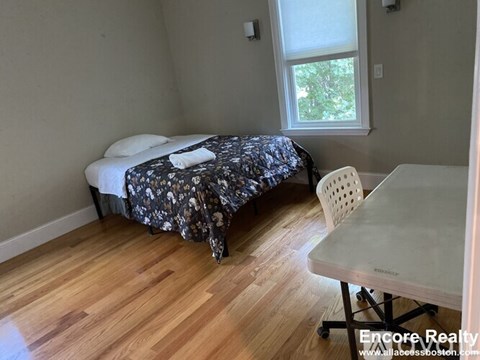 A room with a bed, a chair, and a table.