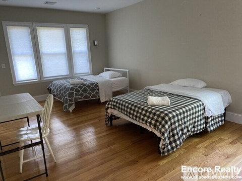 A bedroom with two beds and a table.