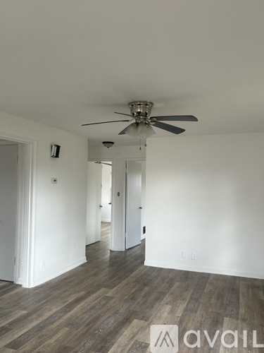 A room with a ceiling fan and wooden flooring.