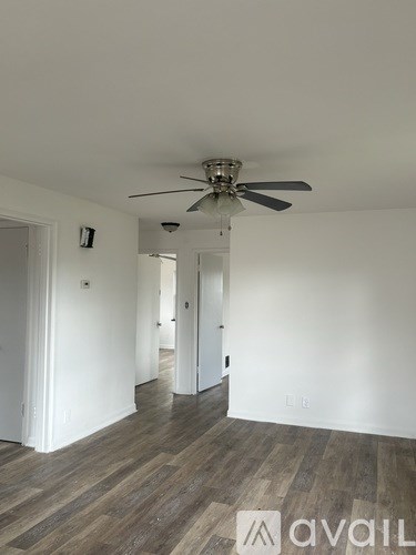 A room with a ceiling fan and wooden flooring.