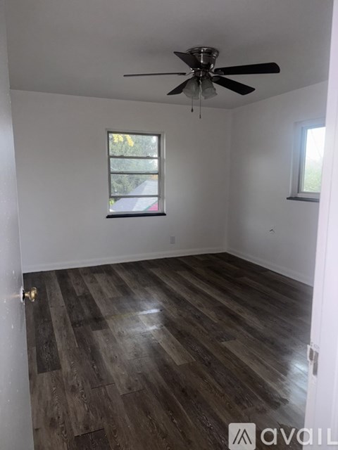 A room with a ceiling fan and wooden flooring.