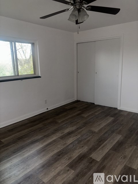 A room with a ceiling fan and wooden flooring.