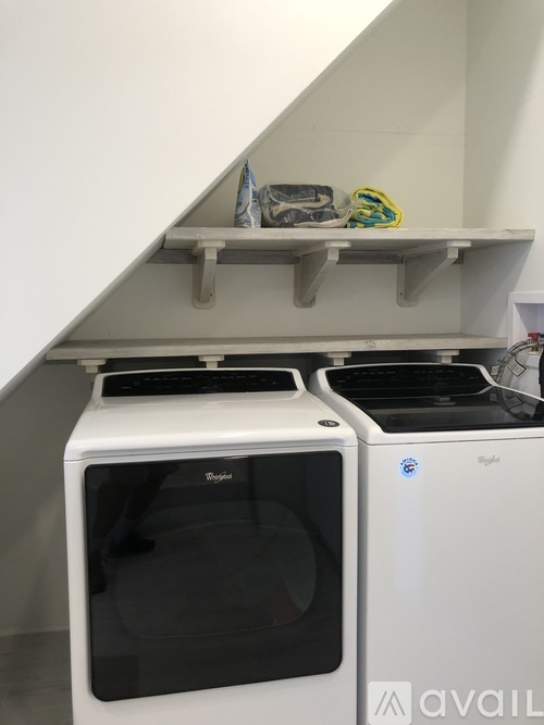 A white dishwasher and oven are on a shelf in a kitchen.