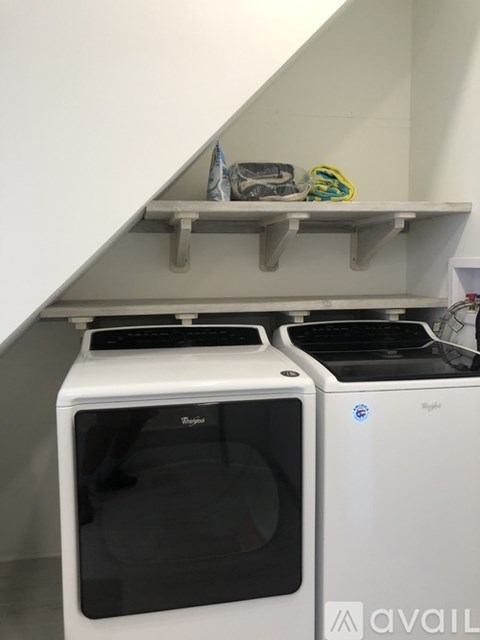 A white dishwasher and oven are on a shelf in a kitchen.