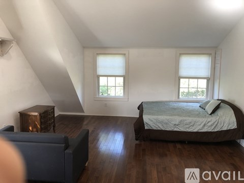 A bedroom with a bed, a couch, and a wooden floor.