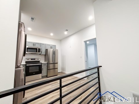 A modern kitchen with stainless steel appliances and wooden flooring.