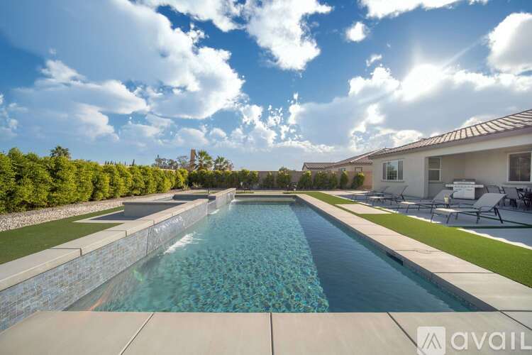 A large swimming pool with a stone wall and a house in the background.