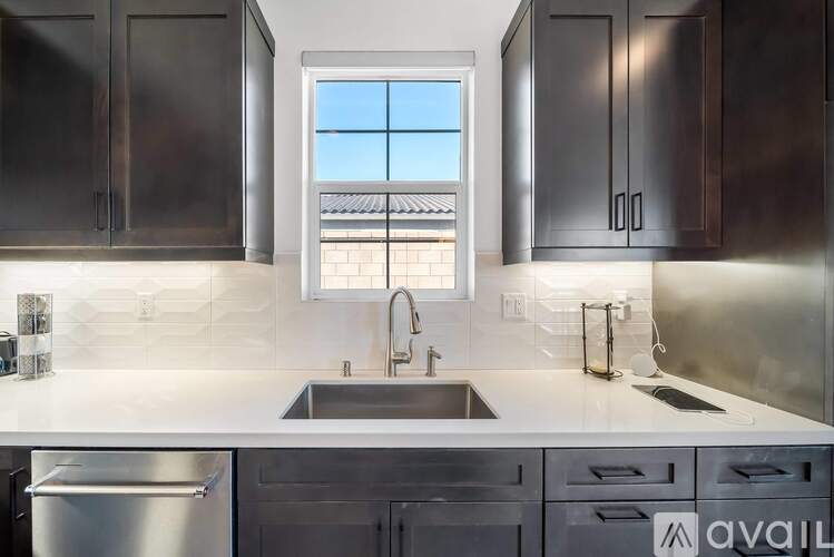 A modern kitchen with dark brown cabinets and a stainless steel refrigerator.