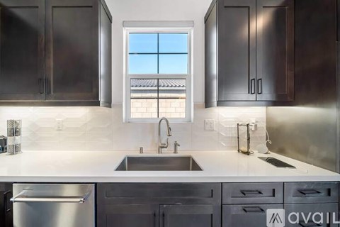 A modern kitchen with dark brown cabinets and a stainless steel refrigerator.