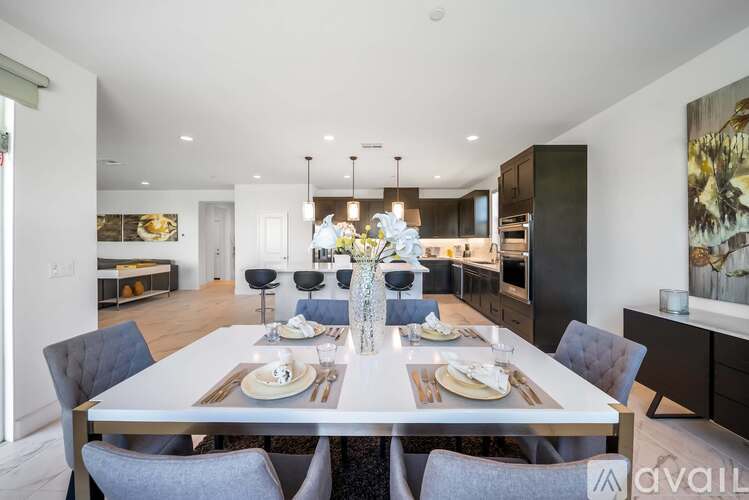 A modern dining room with a long table set for a meal.