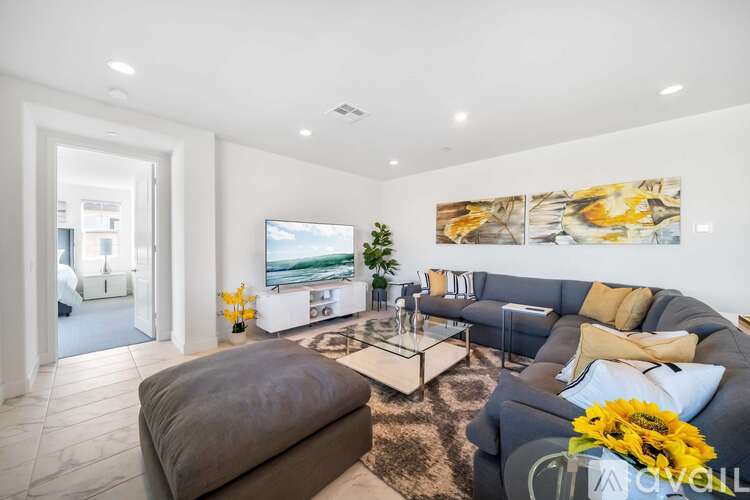 A living room with a grey couch, a coffee table, and a painting on the wall.
