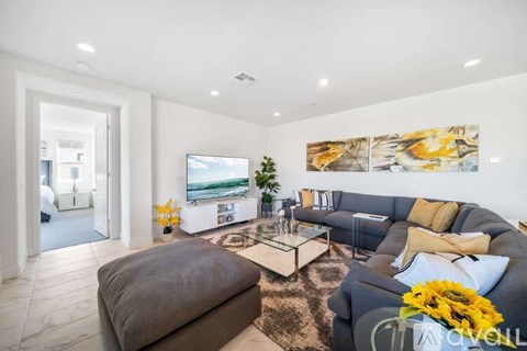 A living room with a grey couch, a coffee table, and a painting on the wall.