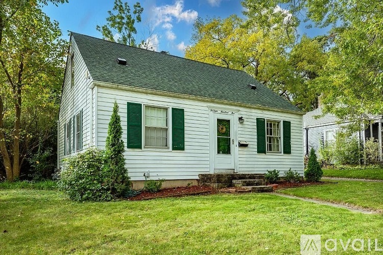 A small white house with green shutters and a green door.