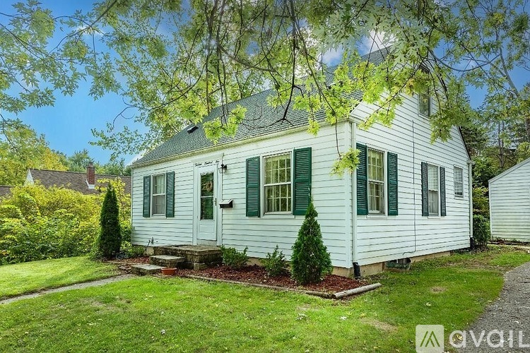 A white house with green shutters is for sale.
