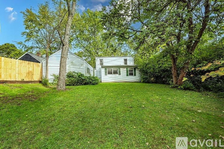 A house with a white fence and trees in the background.