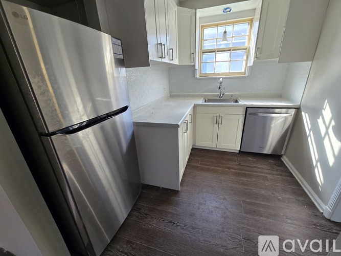 A kitchen with a stainless steel refrigerator and wooden flooring.