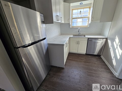 A kitchen with a stainless steel refrigerator and wooden flooring.