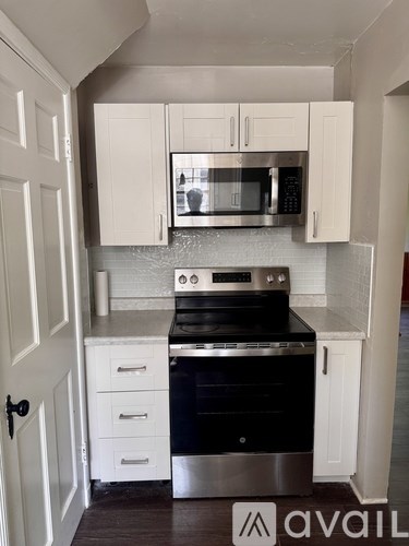 A kitchen with a black stove top oven and white cabinets.