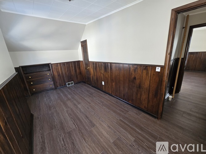 A room with wooden floors and walls, and a door on the right.