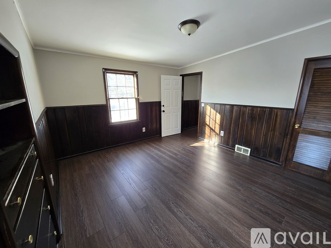A room with wooden floors and a window letting in sunlight.