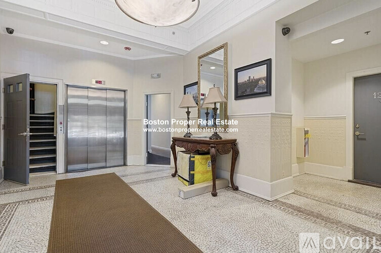 A hallway with a table, chairs, and a framed picture on the wall.