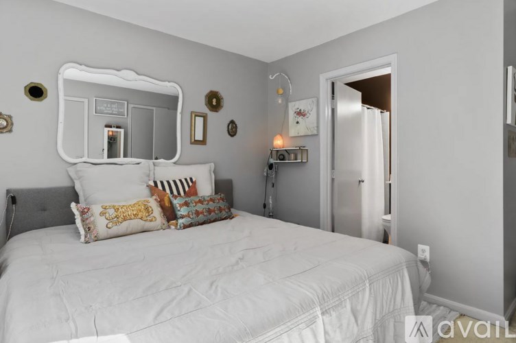 A bedroom with a white bed and a mirror above it.
