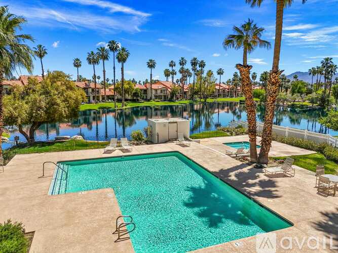 A pool surrounded by palm trees and a mountain in the distance.