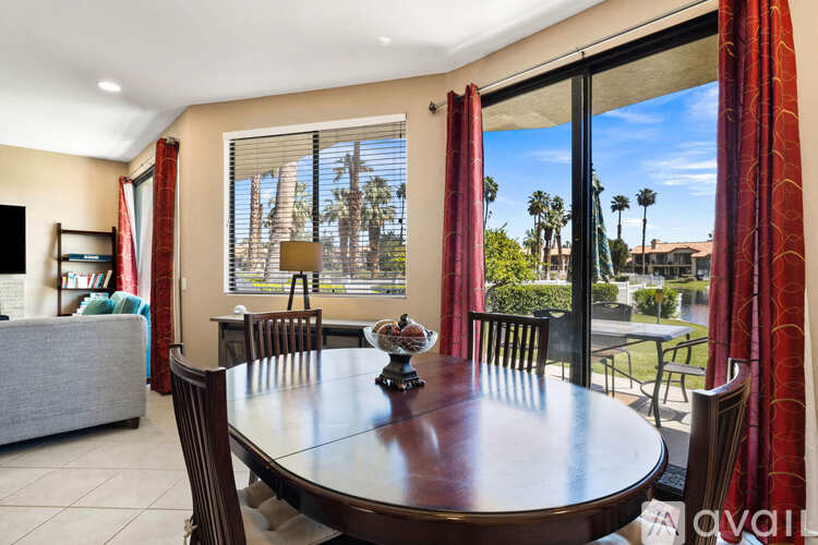 A dining room with a table set for two and a view of a backyard.