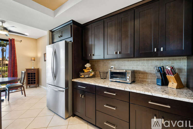 A kitchen with a refrigerator, cabinets, and a counter with a toaster and knives.