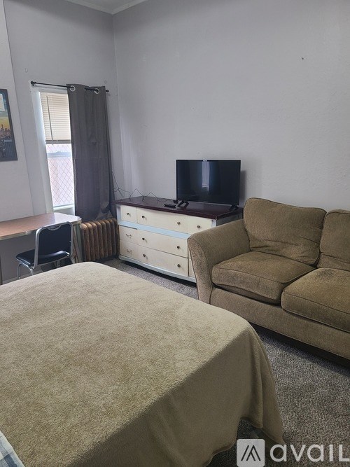 A bedroom with a bed, a couch, and a television.