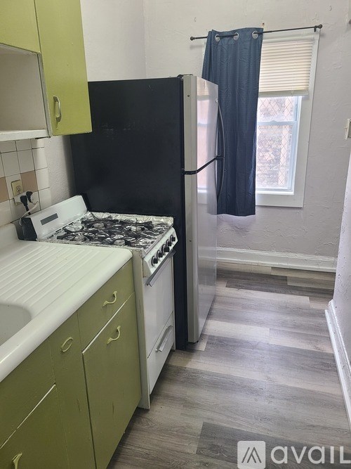A kitchen with a black refrigerator and a white stove top oven.