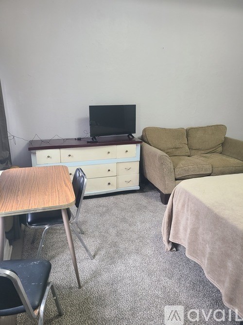 A room with a couch, a desk with a computer, and a bed.
