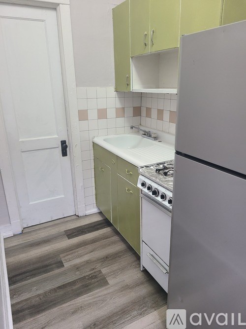 A kitchen with a white door, green cabinets, and a white stove top oven.