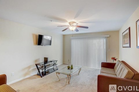 A living room with a glass coffee table and a flat screen TV mounted on the wall.