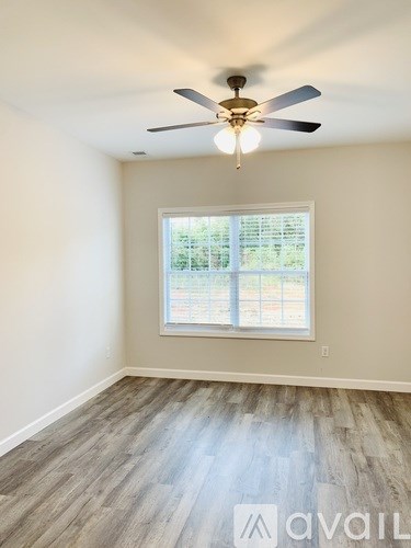 A room with a ceiling fan and a window with blinds.
