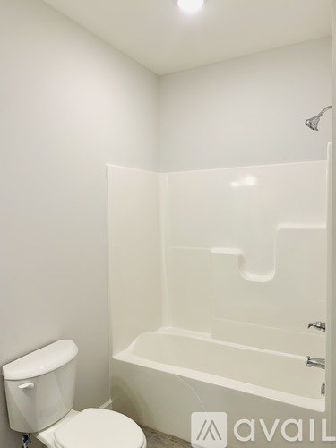 A white toilet sits next to a white bathtub in a bathroom.