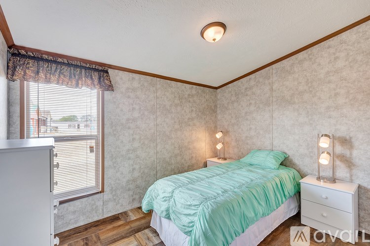 A bedroom with a bed, nightstand, and window.