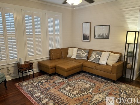 A living room with a tan couch and a rug.